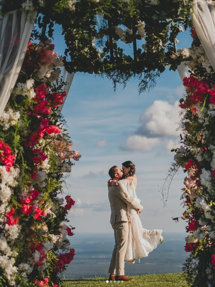 Couple kissing under floral wedding arch