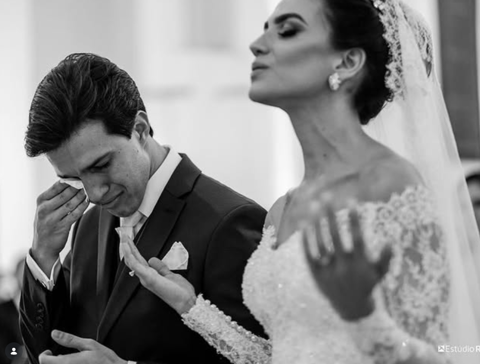 Groom wiping a tear as his bride watches